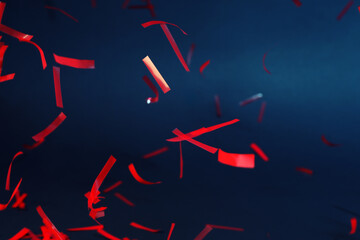 Shiny red confetti falling down on dark blue background