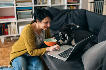 woman playing with her siberian husky puppy at home