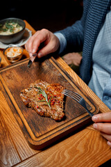 Businessman eating rib steak on wooden tray at restaurant