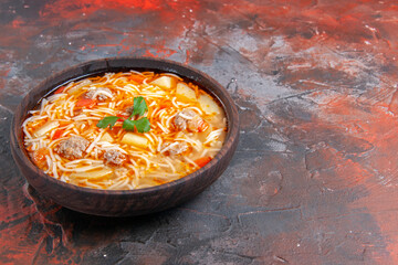 Horizontal view of delicious noodle soup with chicken in a brown bowl on the dark background