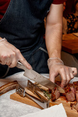 Waiter with gloves cuts Tomahawk steak on a beef bone into pieces for restaurant guests. Close-up of hands
