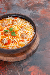 Vertical view of delicious noodle soup with chicken on wooden cutting board on dark background