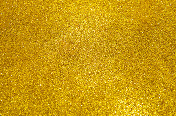 Gold glitter selective focus. Christmas abstract background. Defocused lights texture. Abstract bokeh lights. Shiny sparkle yellow metallic glitter texture. Glamorous abstract background.