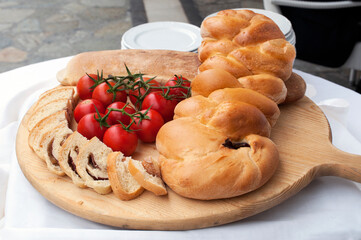 A chopping board with a braid of bread stuffed with salami and cheese and cherry tomatoes on the table.