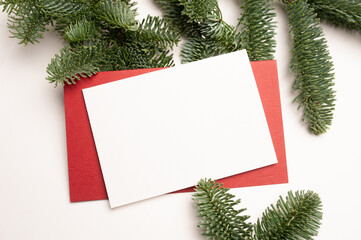 Fototapeta na wymiar Christmas greeting card with envelope on wooden white background with fir tree branches and happy new year decorations. Top view copyspace