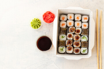 Mixed sushi in box. Japanese sushi food in box on white background with copy space. Top view of sushi in box with ginger, soy and wasabi.