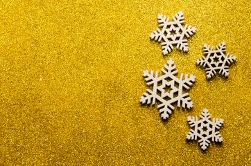 Christmas abstract background. Abstract bokeh lights. Shiny sparkle metallic glitter texture. White decorative snowflake on yellow shiny background with copy space. Top view, flat lay.