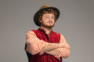 Obraz premium Hands crossed. Happy smiling man dressed in traditional Austrian or Bavarian costume gesturing isolated on grey studio background. Copyspace. The celebration, oktoberfest, festival, traditions concept