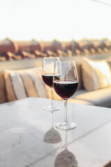 Two glasses of red wine on a rooftop terrace, sunset light 