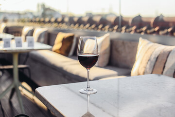 A glass of red wine on a rooftop terrace, sunny evening