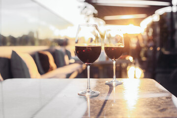 Two glasses of red wine on a rooftop terrace, sunset light 