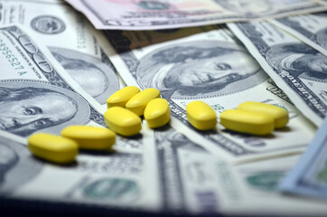 Yellow pills on a background of dollars. Expensive treatment, medicine. Drugs, prohibited substances, psychotropics, coronavirus