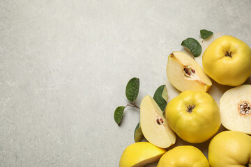 Fresh ripe organic quinces with leaves on grey table, flat lay. Space for text