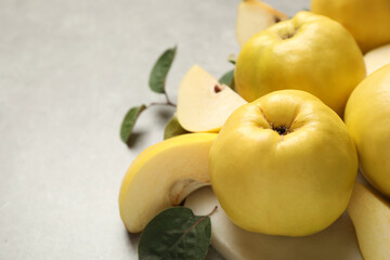 Fresh ripe organic quinces with leaves on grey table, closeup. Space for text
