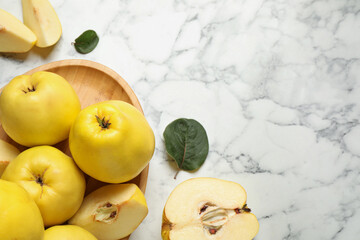 Naklejka na ściany i meble Fresh ripe organic quinces with leaves on white marble table, flat lay. Space for text