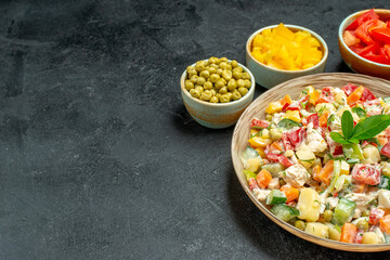 side close view of bowl of vegetable salad with different vegetables on side and free place for your text on dark grey background