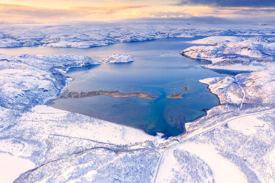 Aerial view of Norwegian County Road 98 along snowy mountains above Laksefjorden, Lebesby, Kunes, Troms og Finnmark, Arctic