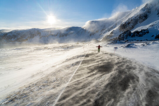 Man rejoices on icy empty road along Barents Sea during the Arctic windstorm, Berlevag, Varanger Peninsula, Finnmark