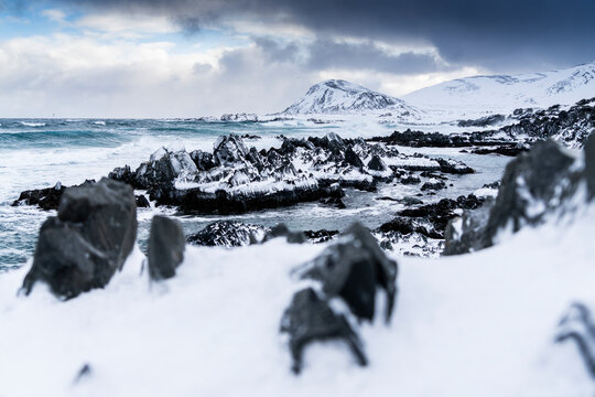Cliffs covered with snow on coastline of the cold Barents Sea, Sandfjorden, Arctic Ocean, Varanger Peninsula, Finnmark