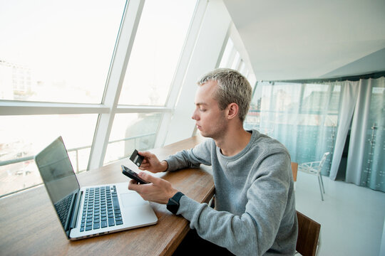 Man gives number of his credit card to the customer to receive payment for the work. White room with panoramic windows on background. Salary time concept. Freelance job concept.