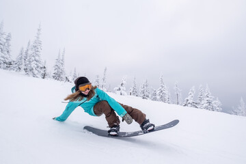 Fototapeta na wymiar Snowboarder female riding down slop in winter ski resort , doing lazy boy snowboarding trick
