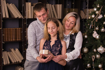 Happy beautiful family in a Christmas interior of an apartment or house, near an elegant Christmas tree