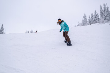 Fototapeta na wymiar Snowboarder female riding on winter snow cowered slop on snowboard. Powder Day, winter holiday in ski resort