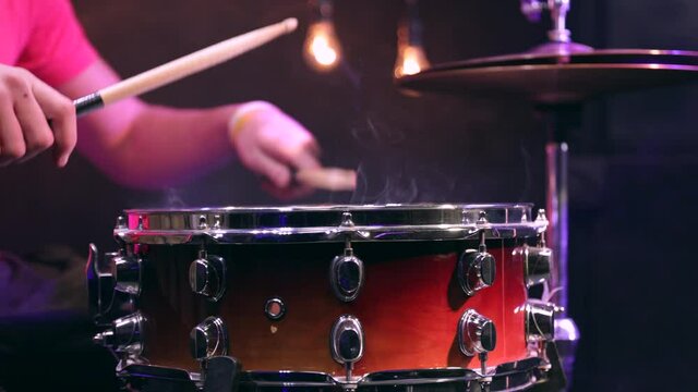 Man playing on snare drum with drumsticks. Closeup.