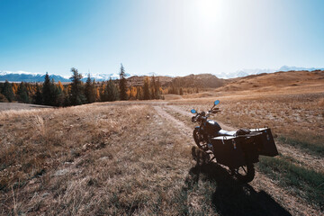 Motorcycle on mountain top, river, snow mountains peaks on background. Off road moto travel in beautiful places