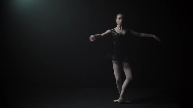 Young graceful woman ballerina in black dress doing a pirouette
