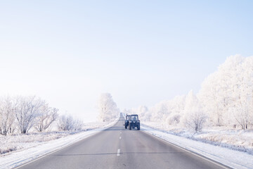 Tractor on the winter road, sunny day, snow cowered trees