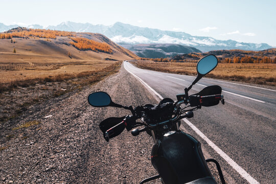 Motorcycle on the road in beautiful mountain landscape. Snow mountains peaks skyline