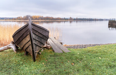 Old wooden boat on the shore of beautiful misty lake and autumn forest landscape. Autumn forest and lake background.