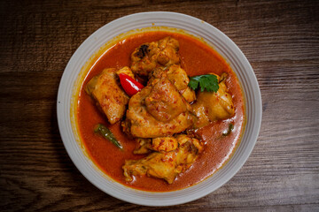 Ayam Kalio Padang or wet saucy chicken rendang top view on wooden background.