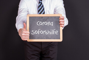 Unternehmer mit einer Tafel auf der Corona Soforthilfe steht