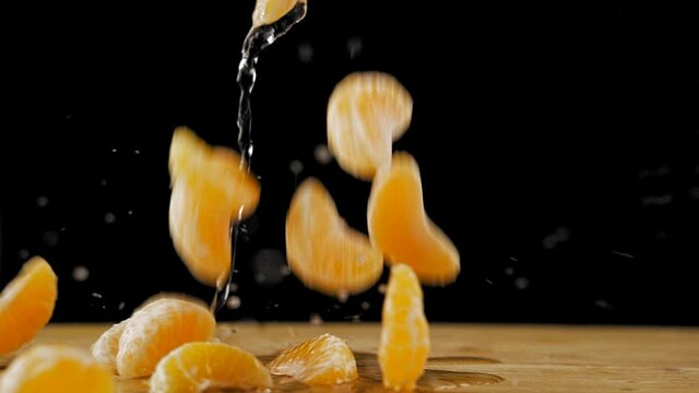 Falling orange slices on a black background, slow motion video