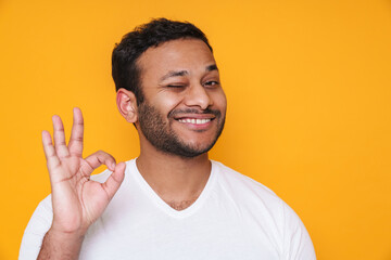 Asian young unshaven man smiling and gesturing okay sign