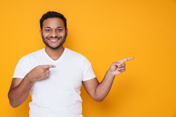 Asian young unshaven man smiling and pointing his fingers aside