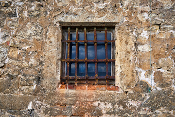 Fototapeta na wymiar An old window in the castle with a rusty steel grate