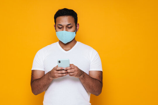 Asian focused man in face mask using mobile phone