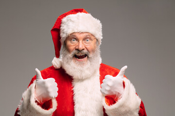 Senior man like Santa Claus isolated on grey studio background. Caucasian bearded male model in traditional costume. New Year 2021, gifts, holidays, winter mood. Copyspace for your ad. Hangover