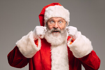 Senior man like Santa Claus isolated on grey studio background. Caucasian bearded male model in traditional costume. New Year 2021, gifts, holidays, winter mood. Copyspace for your ad. Hangover