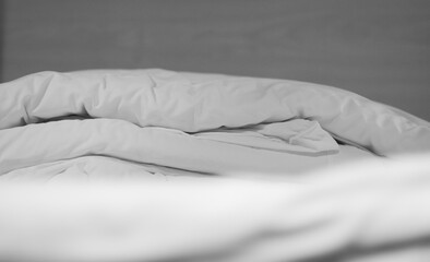 Soft and calm atmosphere image of all white bed room. Pillows and blanket on empty bed, close up.