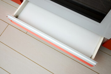 Upscale Maple Red kitchen drawer for plates or dishes shelf cabinet. Pull out rack cabinet filler pantry under oven. Horizontal drawer shelf with orange front wooden panel top view.