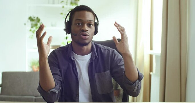Close-up view from webcam of African American guy student studying remotely from home. Mixed race businessman advises clients wears headphones and teacher conducts online lesson, support line concept