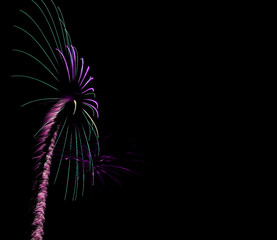 Bright purple and green trail of light up to a exploding splash of color. Left side of image, isolated on a black background.