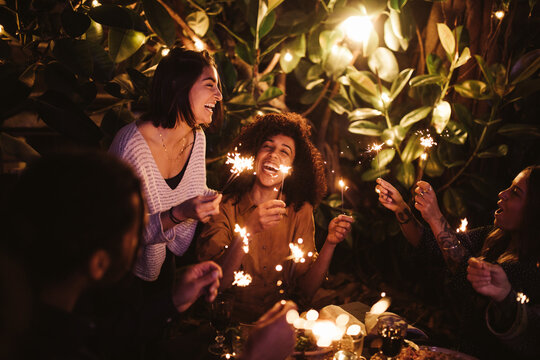 group of friends cheering with sparklers on party together 