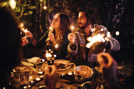 happy young adult couple celebrating at party with sparklers 