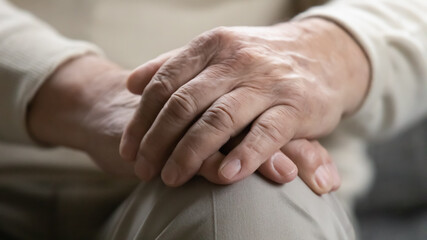 Fototapeta premium Time teaches us patience. Close up view of older generation male palms joined on his lap. Problems of retired people. Health failing with age. Patronage and psychological support for elderly persons