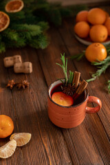 Mulled wine winter hmemade drink for holiday celebration with orange mandarins, tangerin on the wooden table